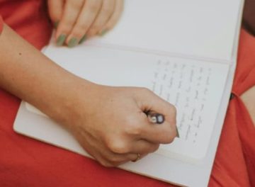 foto van een vrouw in een rode jurk die schrijft in een schrift